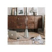 Laptop on a wooden floor with a diffuser emitting steam, a dresser in the background.